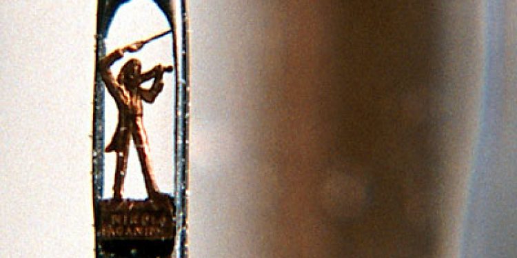 Золотая статуэтка Паганини помещенная внутри ушка иглы. Лицо музыканта в 50 раз меньше крупицы.